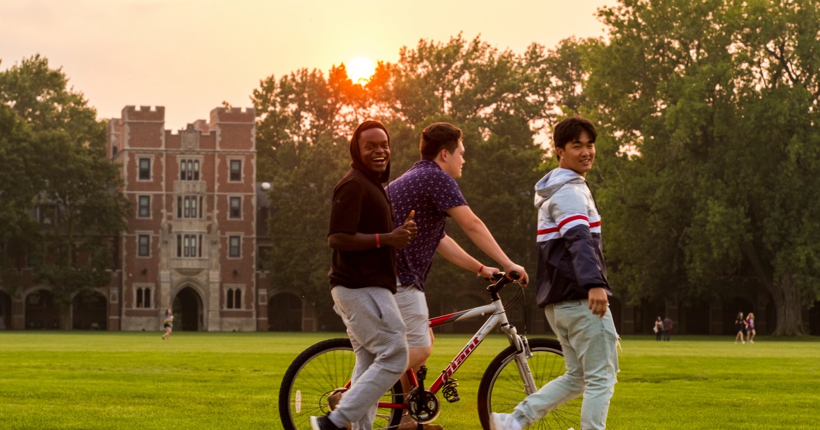 Students walking and biking through mac field