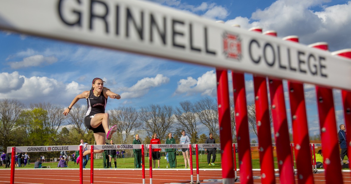 A student athlete jumps over a hurdle.