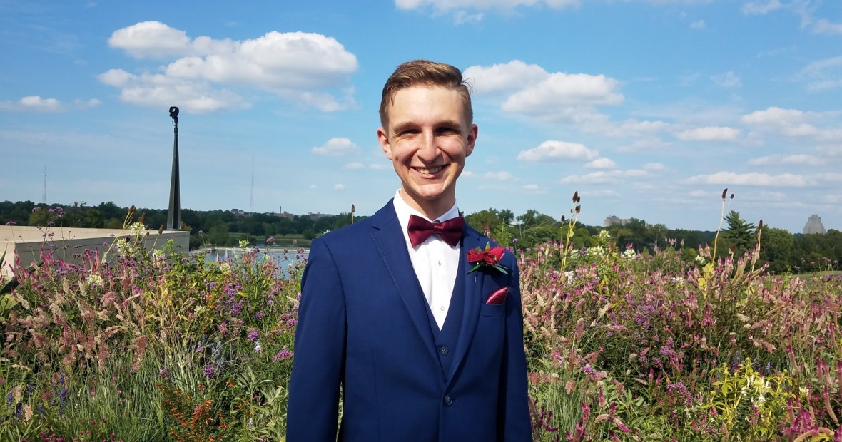 Joe Beggs ’19 wears a suit and stands in a field