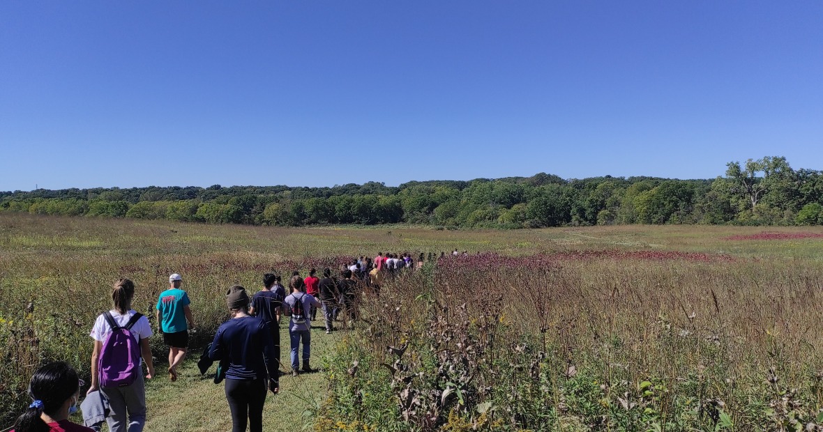 Large group walking on wide path through prairie