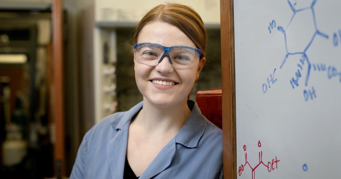 Jennifer Fulton wearing lab goggles standing by whiteboard