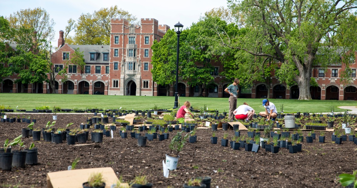 Students in prepared ground planting prairie flora on North Campus with Gates Rawson Tower in the background
