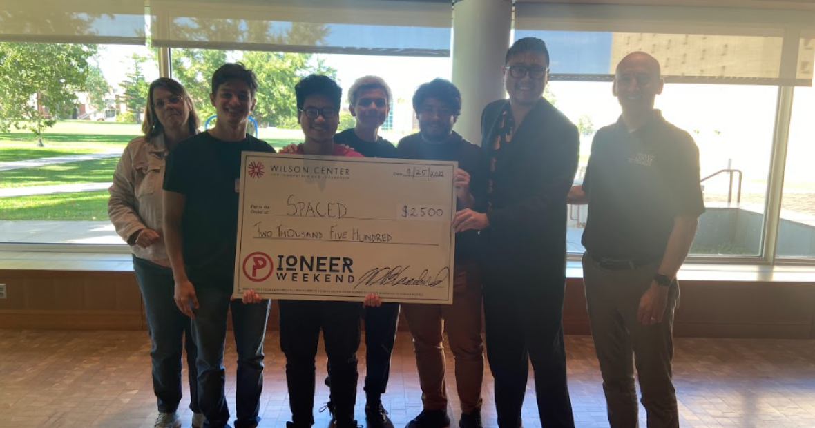 Pioneer Weekend's first-place team of five students with their oversized prize check. 