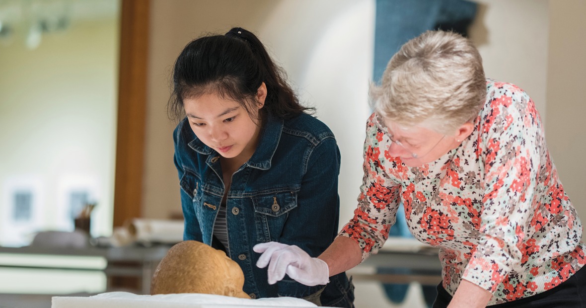 A professor and student examine a marble Roman portrait head, believed to be from 1st century, in the print study room of the Burling Library