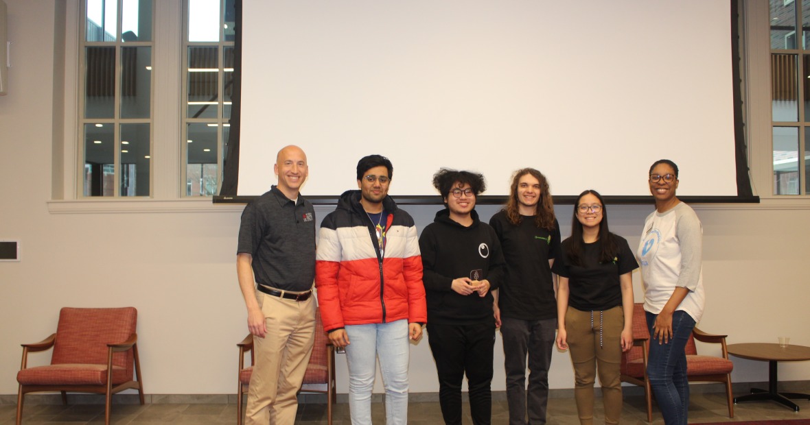 Third-place team holding their trophies, with Jeff Blanchard, Wilson Center director, and an event judge.