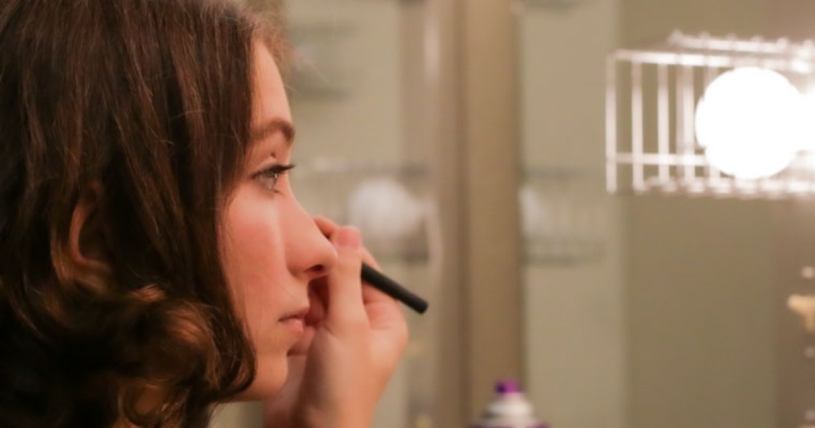 A performer puts eyeliner on in the makeup room