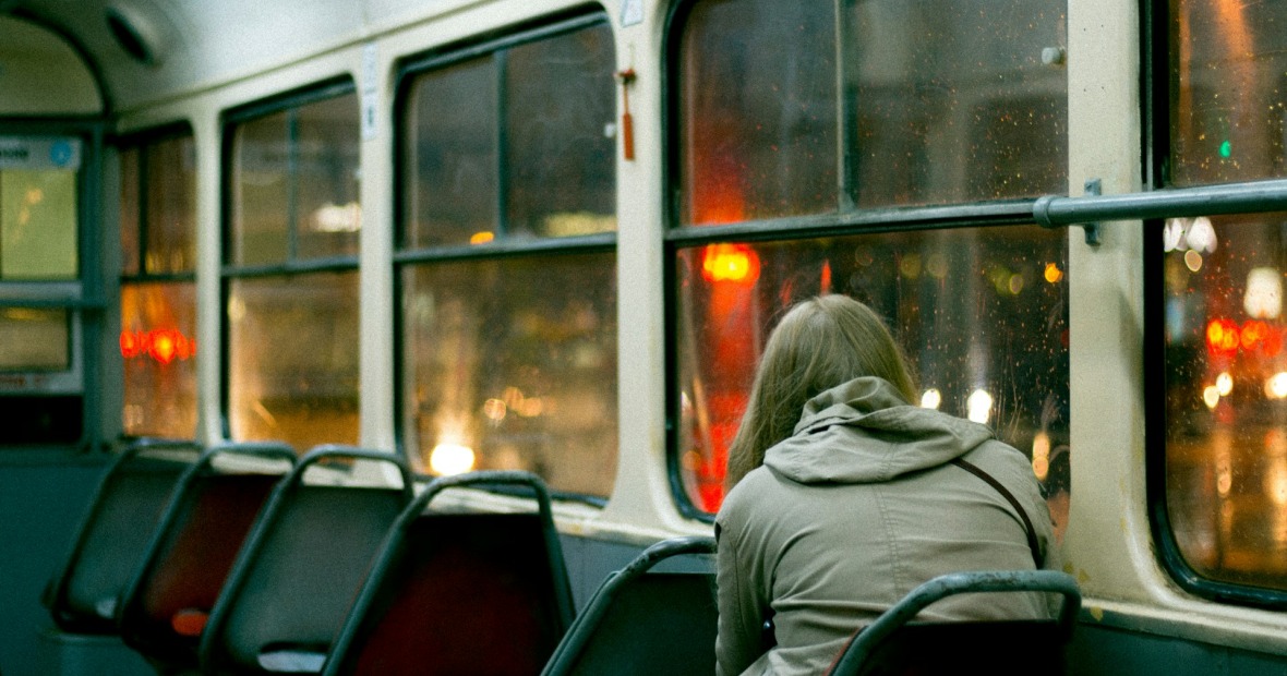 A woman looks out the window of a city bus
