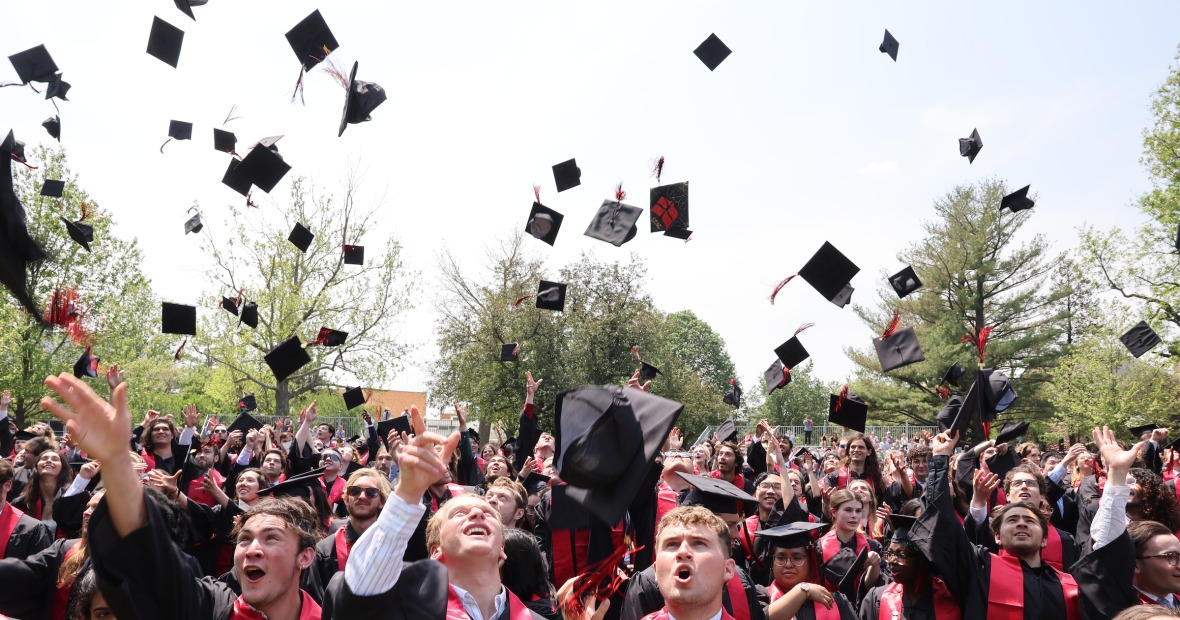 students throwing graduation hats in air 