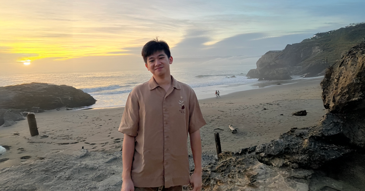 Nam Do on a beach with a beautiful sunset behind him