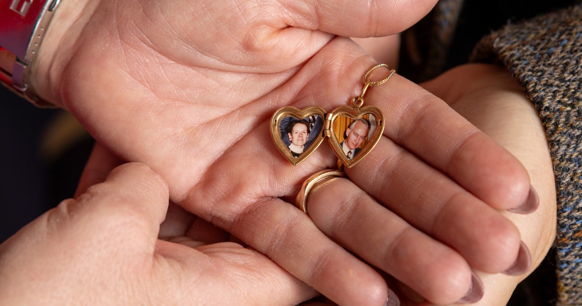 Two sets of hands holding an open locket with pictures Emmett and Pierrette Harris inside.