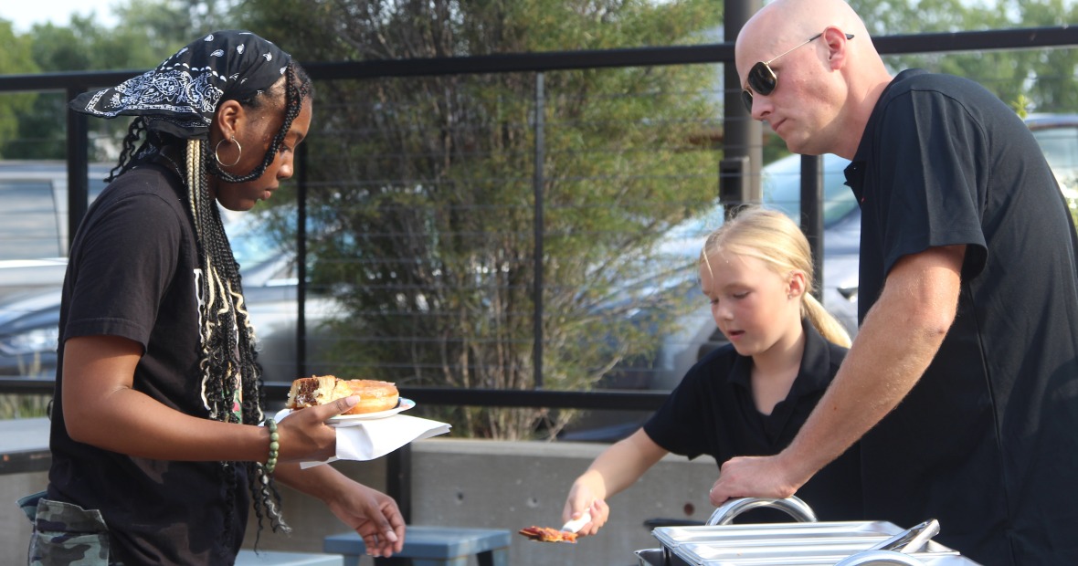 A business owner serves pizza to a Grinnell College student
