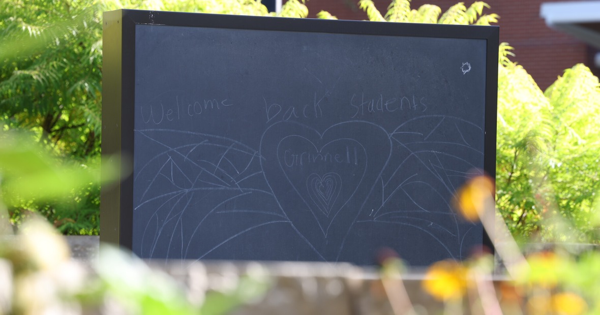 Outdoor chalk board with the words "Welcome back students" and an outline of a heart with "Grinnell" inside.