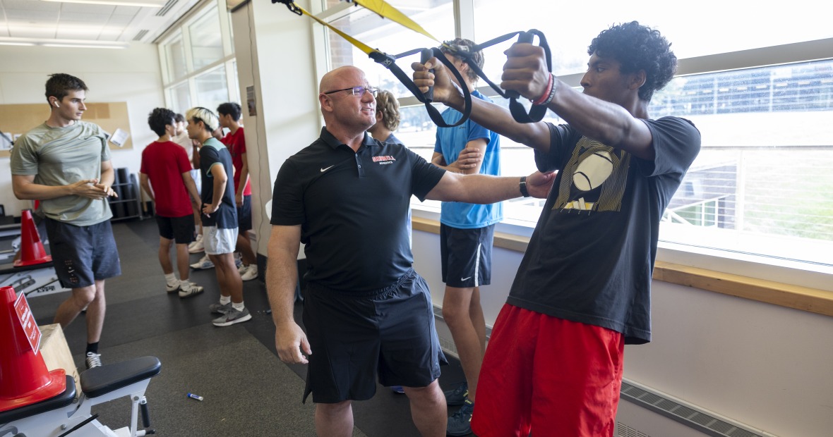 A coach works with athletes in the weight room