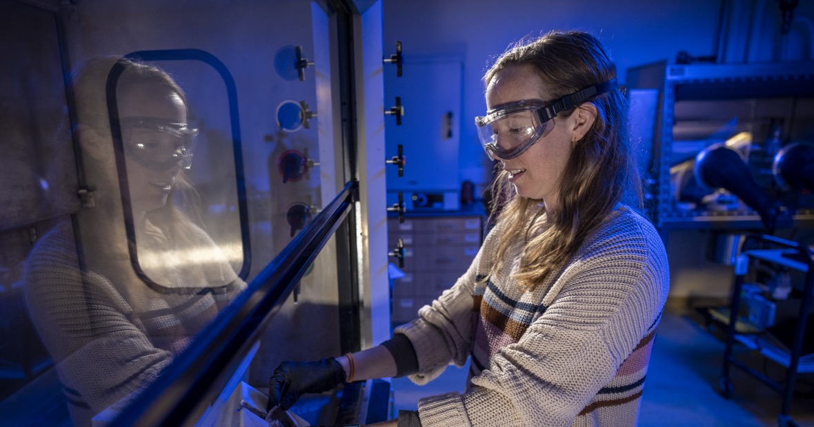 Molly MacInnes standing in profile and wearing lab goggles 