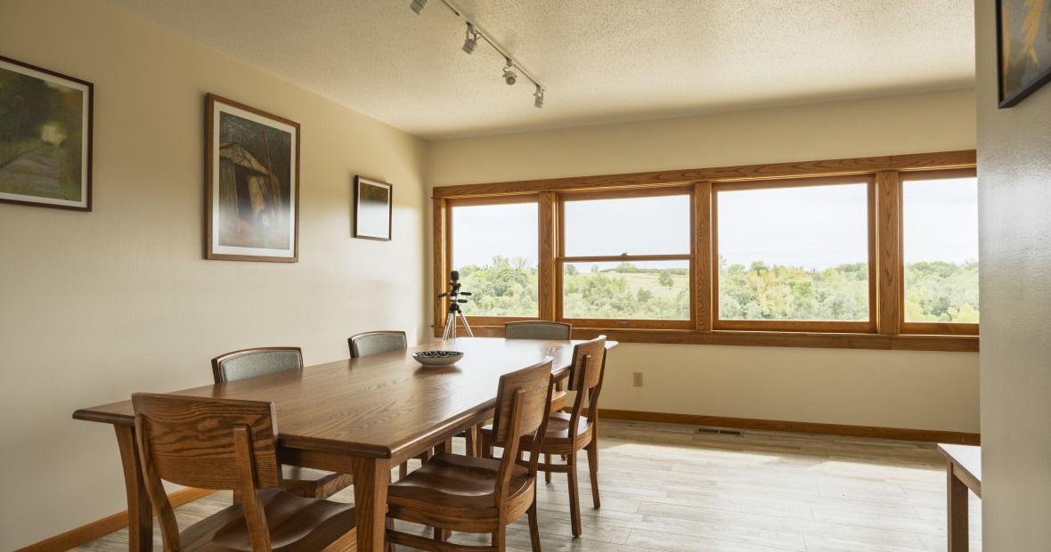 A long dining table in front of a big wall of windows looking out on the prairie landscape