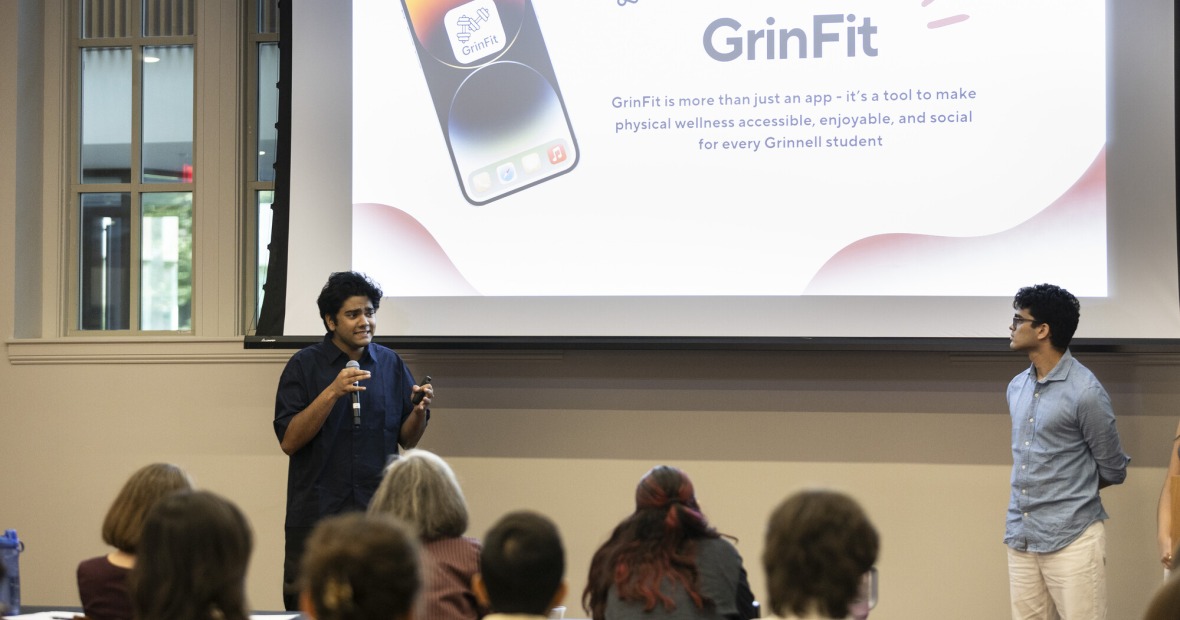 2 students presenting in front of people with a screen that says GrinFit