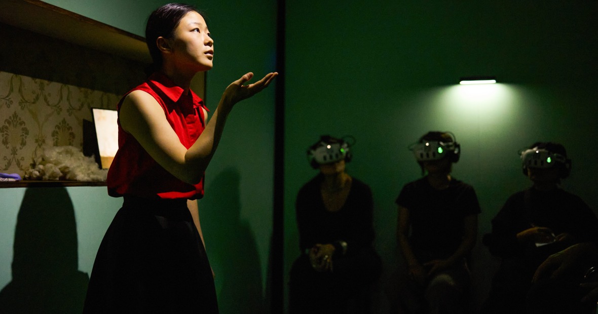 A young woman actress interacts with audience members wearing virtual reality headsets