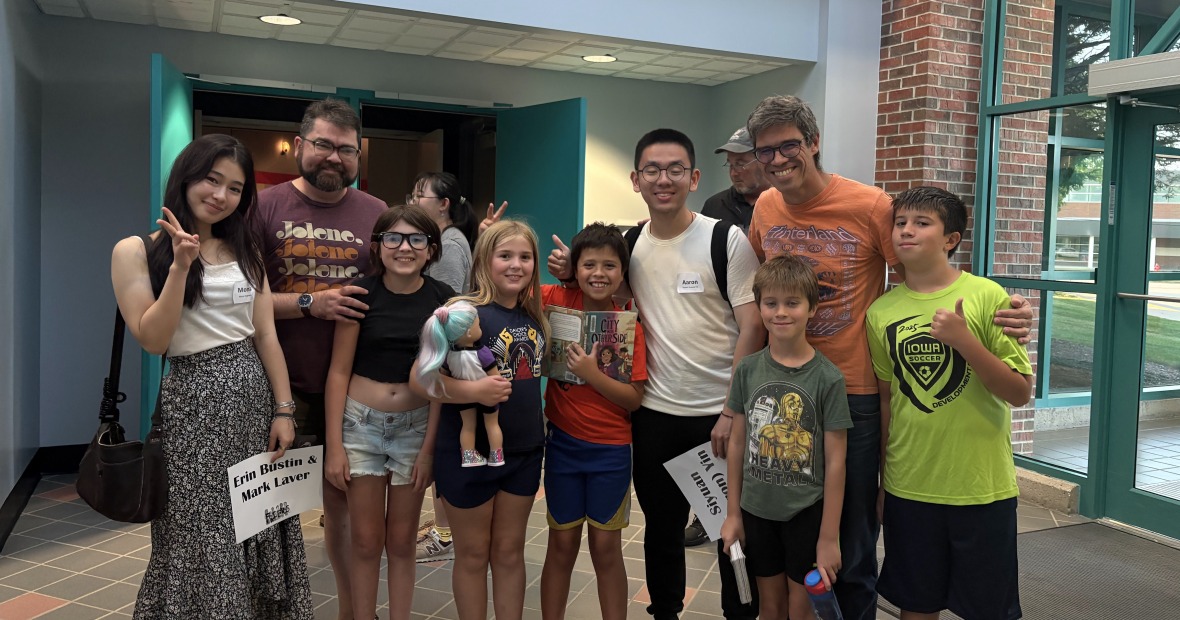 A group of people stand together and smile at the viewer