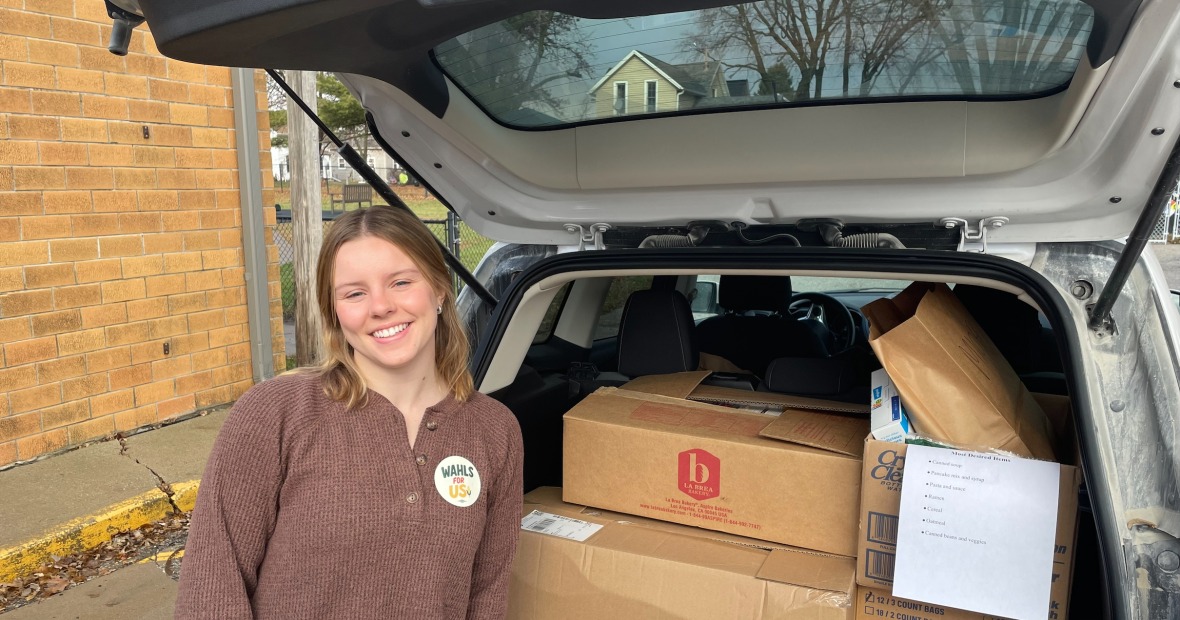 woman standing in back of car with boxes of food