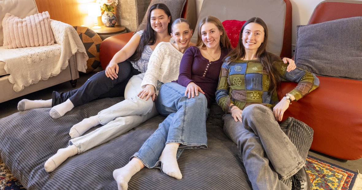 Four smiling young women on a giant beanbag chair