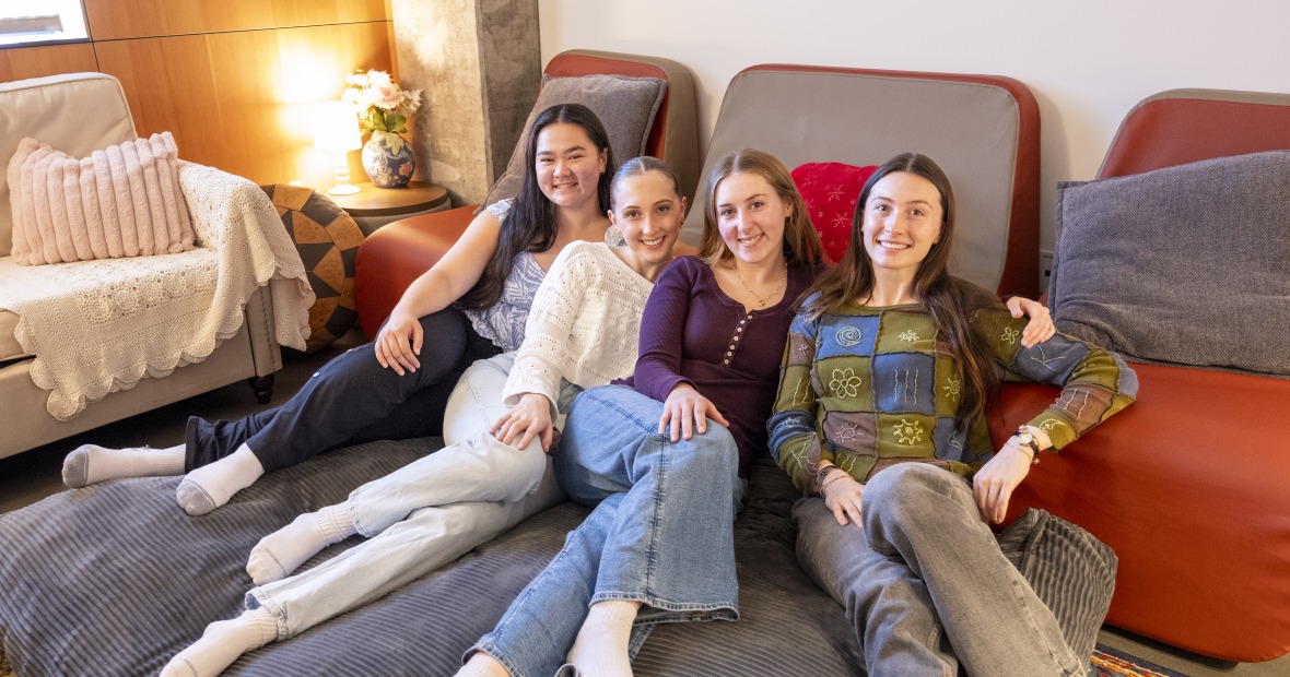 Four smiling young women on a giant beanbag chair