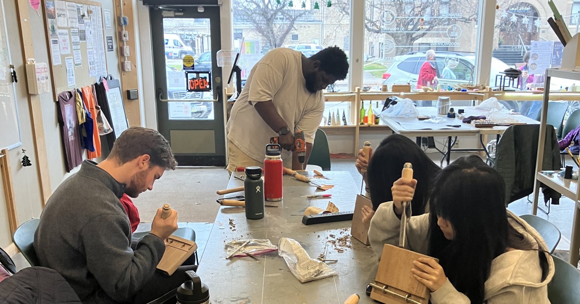 Students work with hand tools to refine their soundboards for the mbira. 