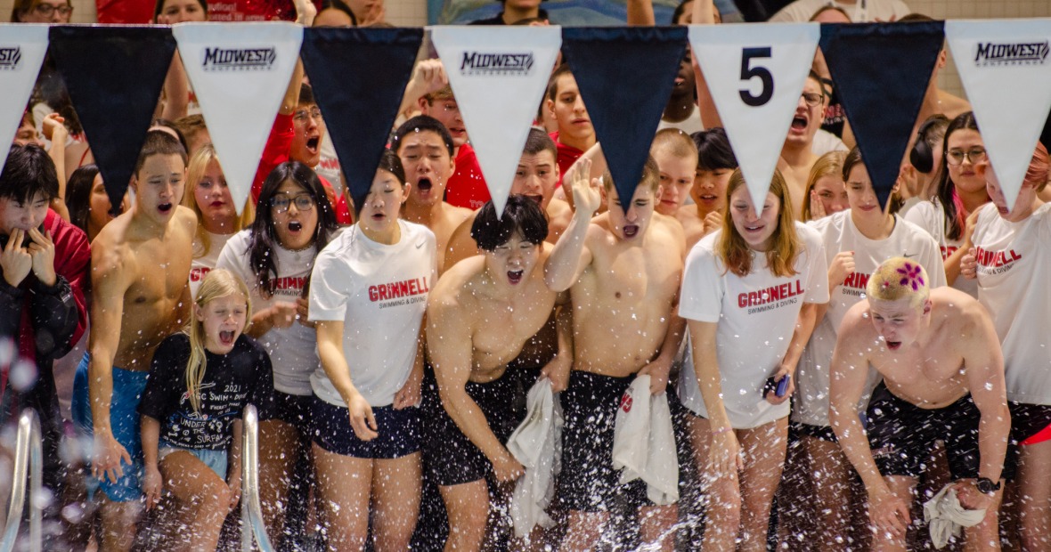 A group of students standing at the edge of a pool and cheering