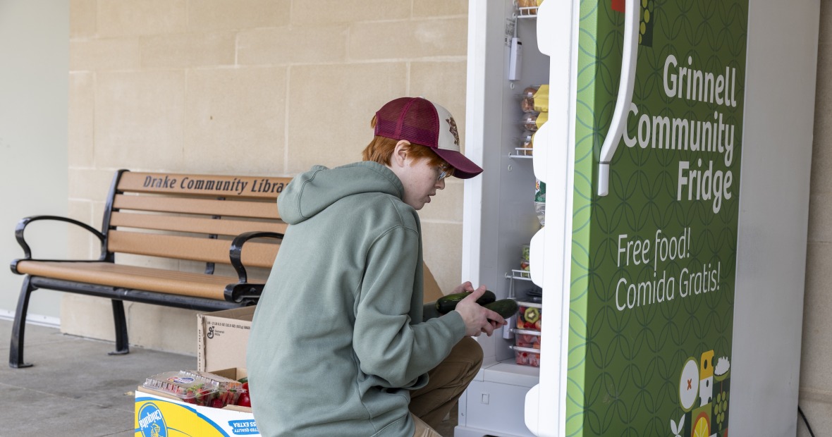 Person in hat stocking the community fridge