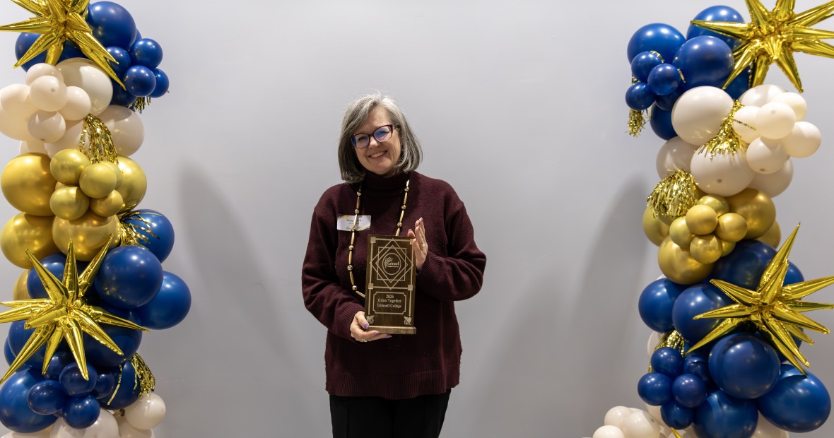 President Harris Holding an award with blue and yellow balloons on side 