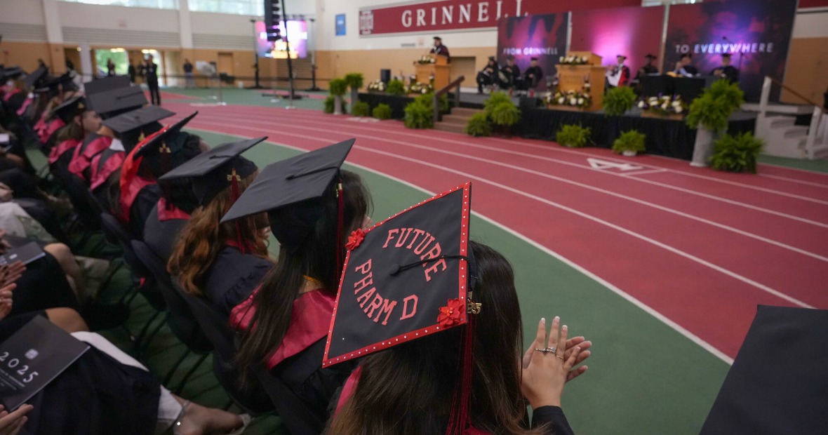 Graduates in the Field House seated in front of the commencement stage.