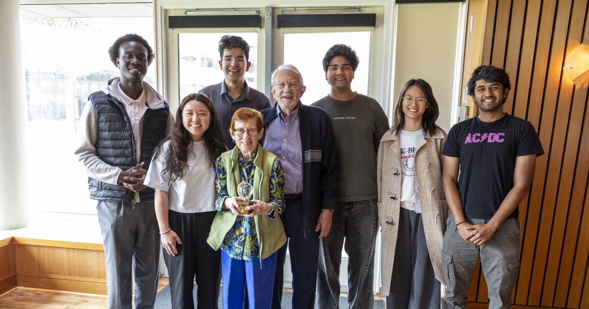 students standing with an older couple with an award 