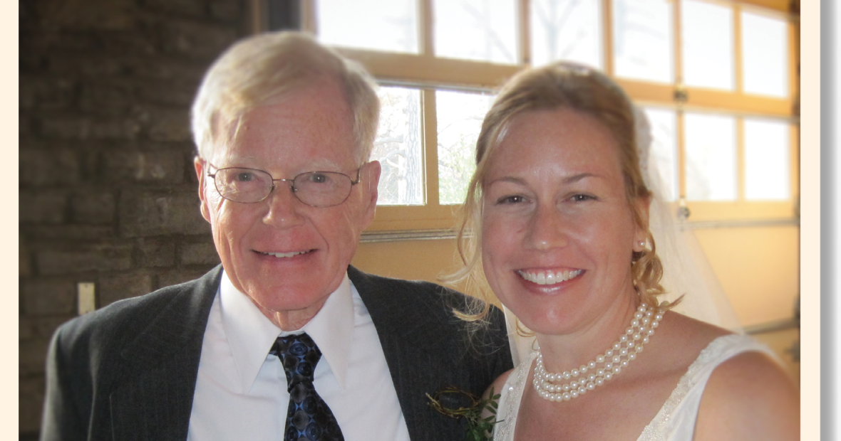 Melanie Drake in her wedding gown and pearls stands next to her father, George Drake.
