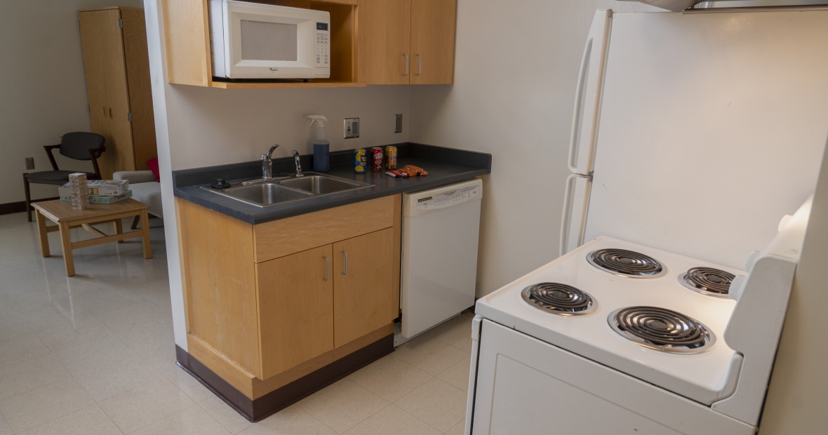 A kitchen with cabinets, sink, stove, and refrigerator.