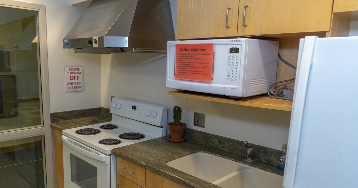 A kitchen with cabinets, sink, stove, and refrigerator.