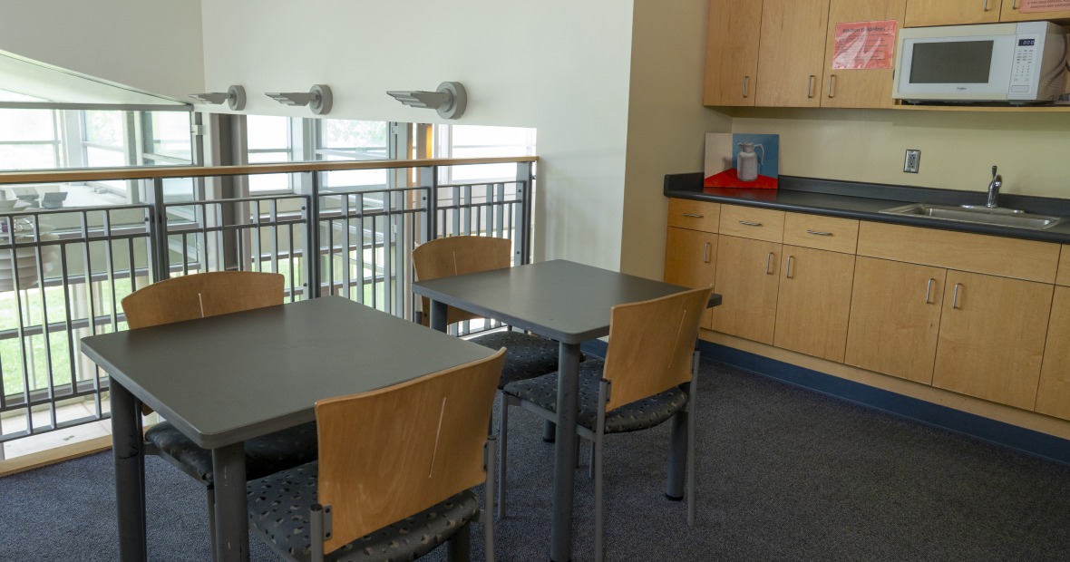 A lounge area with tables and a kitchen.