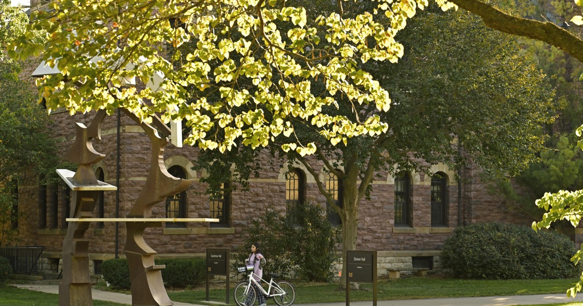 A girl walking a bicycle next to Steiner Hall