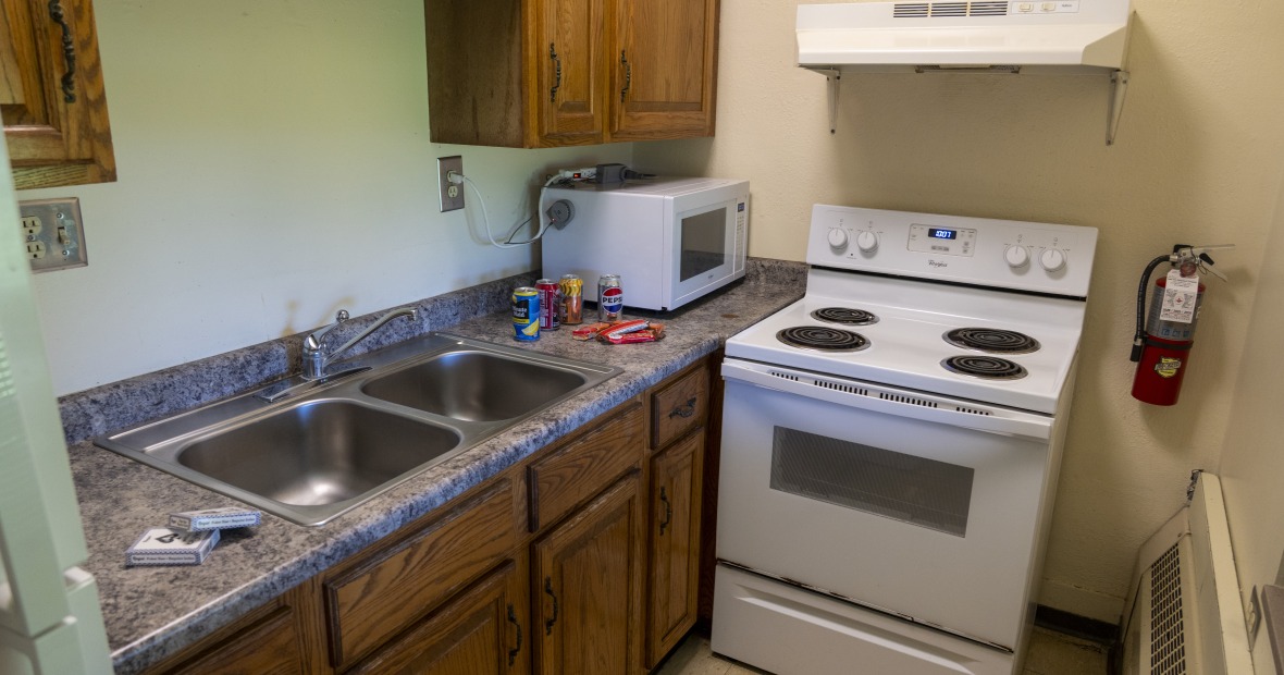 Apartment kitchen with cabinets, a sink, stove, and refrigerator.