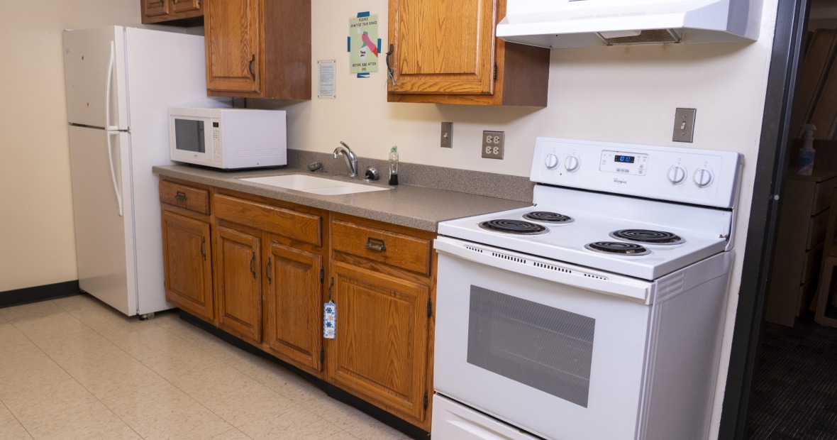 A kitchen with cabinets, sink, stove, and refrigerator.