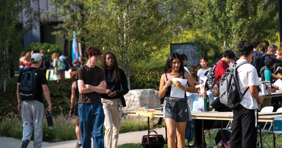 A multi-racial group of students visits tables in an outdoor venue