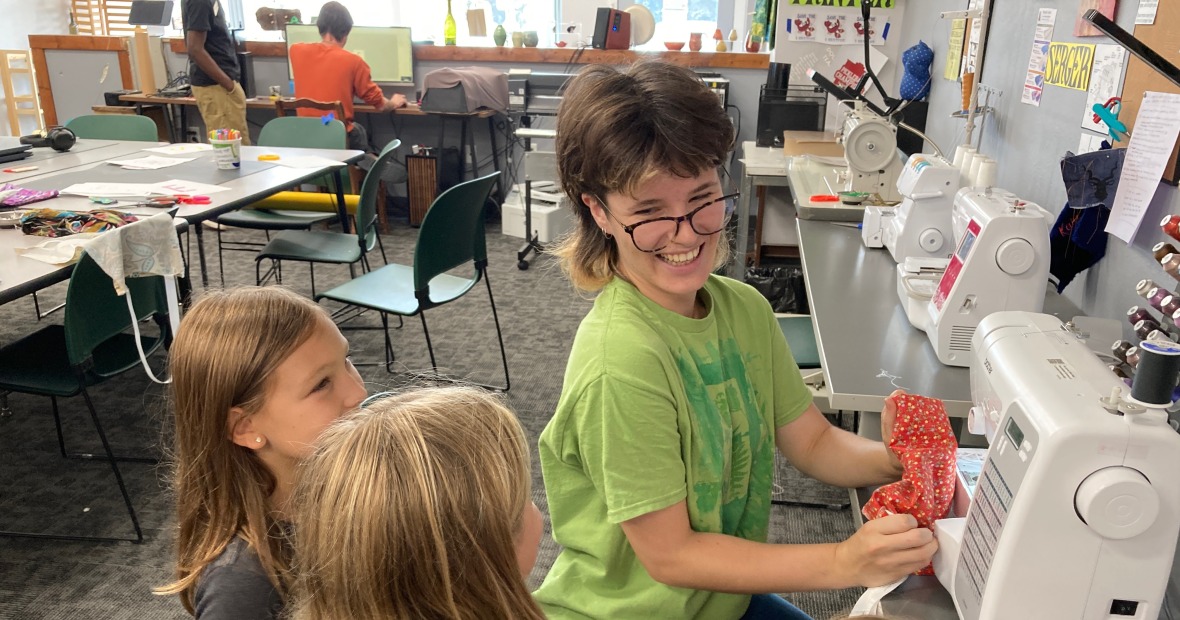 Student with 3 kids at a sewing machine