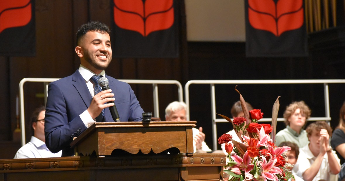Grinnell College alum Nick El Hajj speaks at the podium for at the 2024 baccalaureate ceremony.