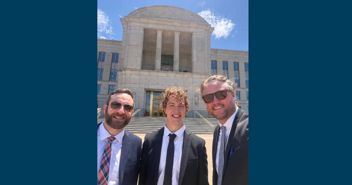 three people in front of building with blue sky 