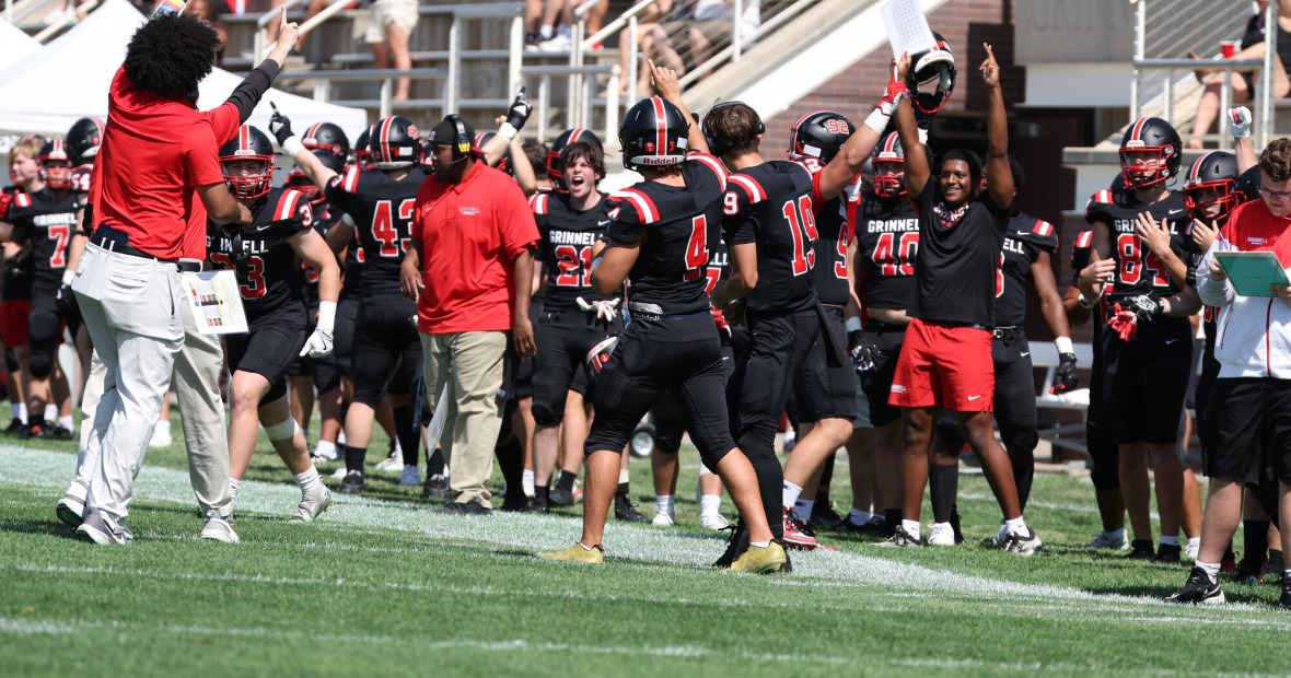 Players and coaches cheer on the sidelines during a football game.