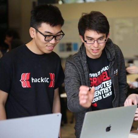 Students standing in front of laptops discussing something on the screen
