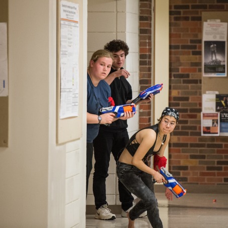Three students with Nerf guns peer around corner of Noyce