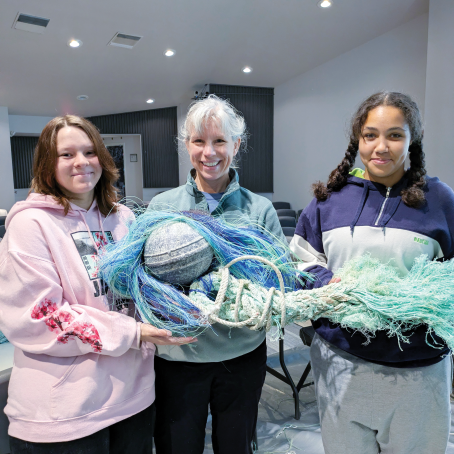 Beran and two young women hold nets and a bouy