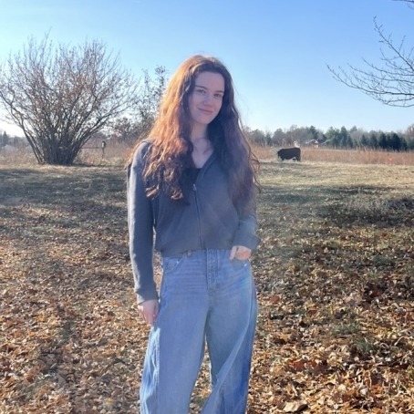 a woman smiles for a photo in a field