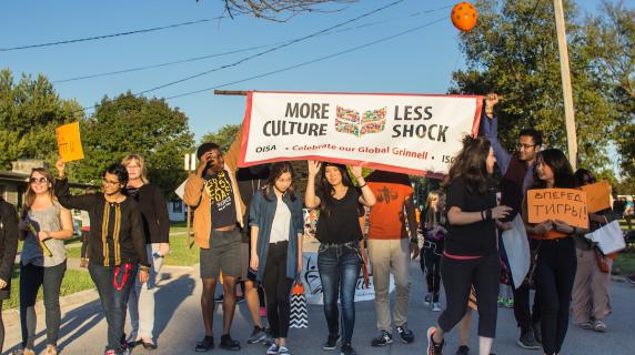 students hold parade banner "More Culture, Less Shock"