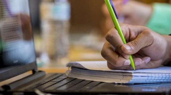 Student taking notes on paper during class