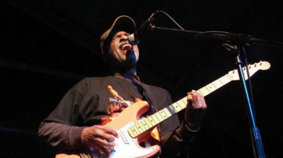 Dartanyan Brown plays bass guitar and sings into a microphone